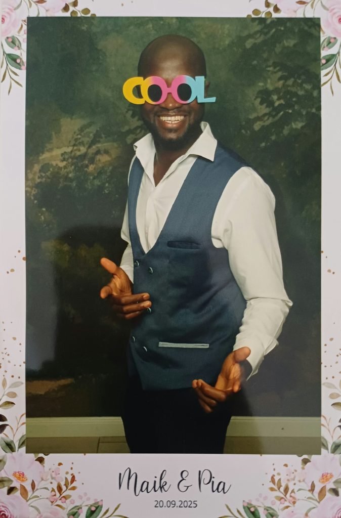 DJ Ajazz im Hemd mit afrikanischem Muster hinter seinem Setup.