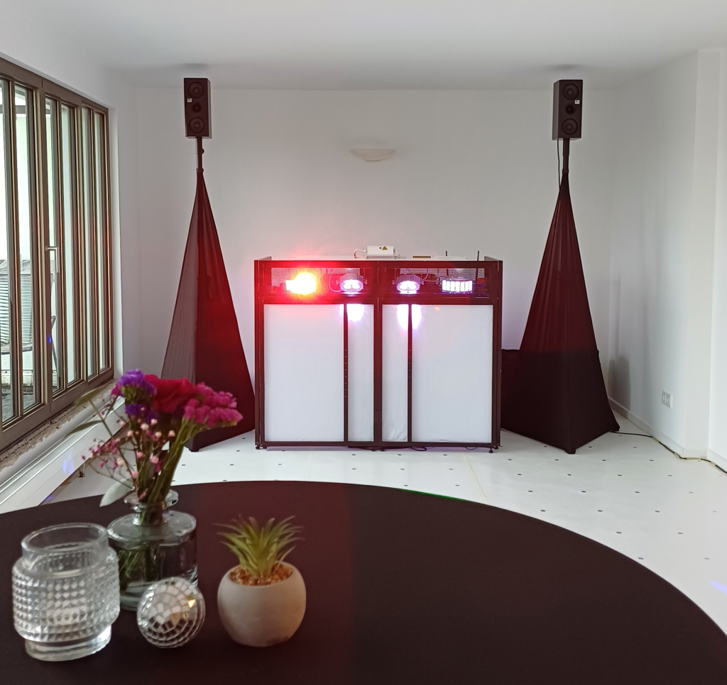 DJ Ajazz im Hemd mit afrikanischem Muster hinter seinem Setup.