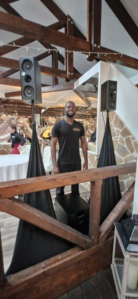 DJ Ajazz im Hemd mit afrikanischem Muster hinter seinem Setup.