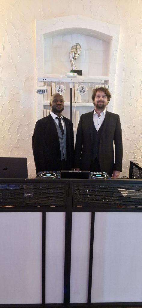 DJ Ajazz im Hemd mit afrikanischem Muster hinter seinem Setup.